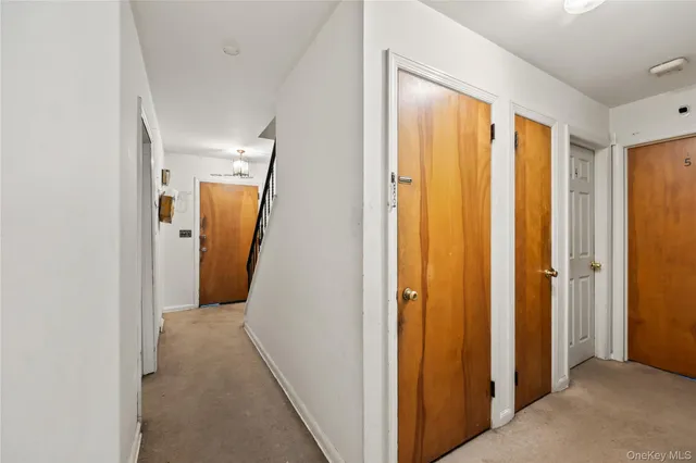 a view of a hallway with wooden floor and a bathroom
