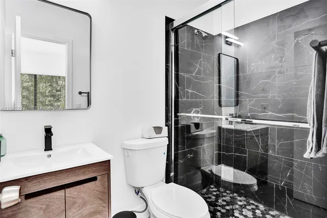 a bathroom with a sink a toilet a mirror and shower