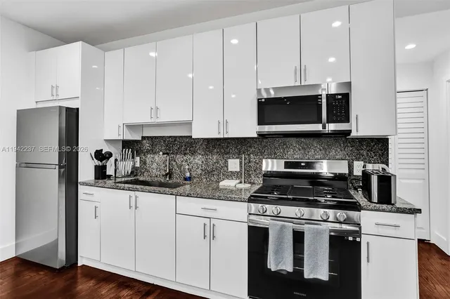 a kitchen with stainless steel appliances granite countertop a stove a sink and a refrigerator