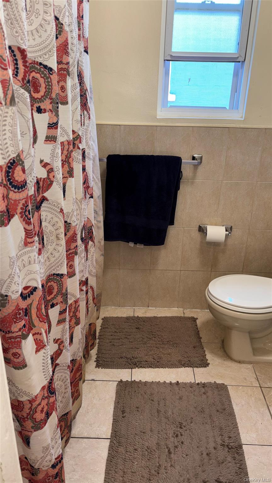 1004 Lenox Road Brooklyn, NY 11212 - Photo 7 of 13 1 Bathroom featuring a white toilet, tile flooring, and partial wall tiling