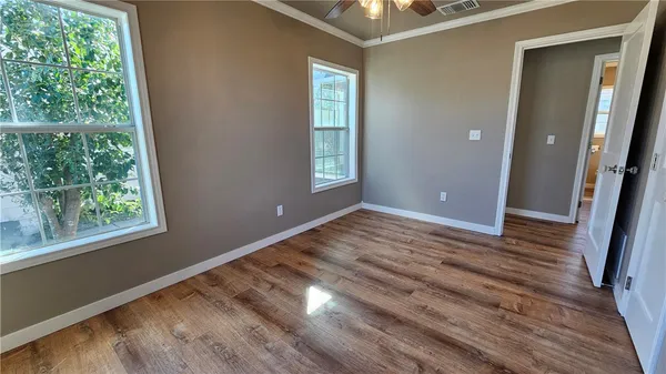 a view of an empty room with wooden floor and a window