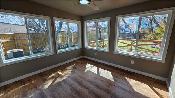 a view of an empty room with wooden floor and a window