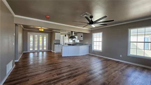 a view of an empty room with window and wooden floor
