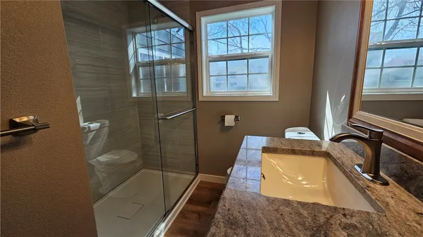 a bathroom with a granite countertop sink a toilet and shower