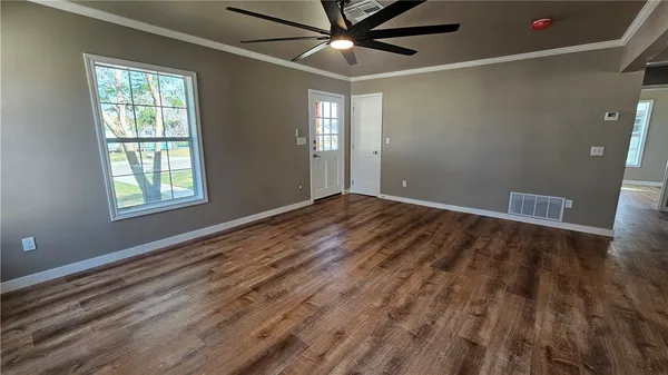 a view of an empty room with wooden floor and a window