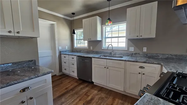 a kitchen with granite countertop a sink stove and cabinets