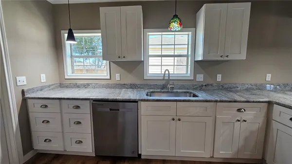 a kitchen with granite countertop cabinets stainless steel appliances a sink and a window