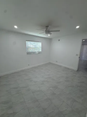 an empty room with a ceiling fan and window