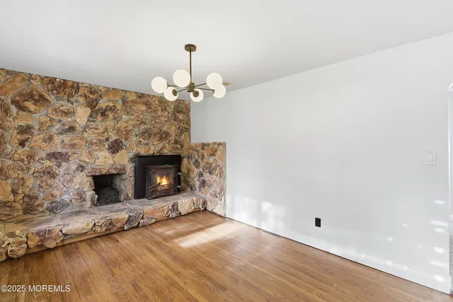 an empty room with wooden floor fireplace and a window