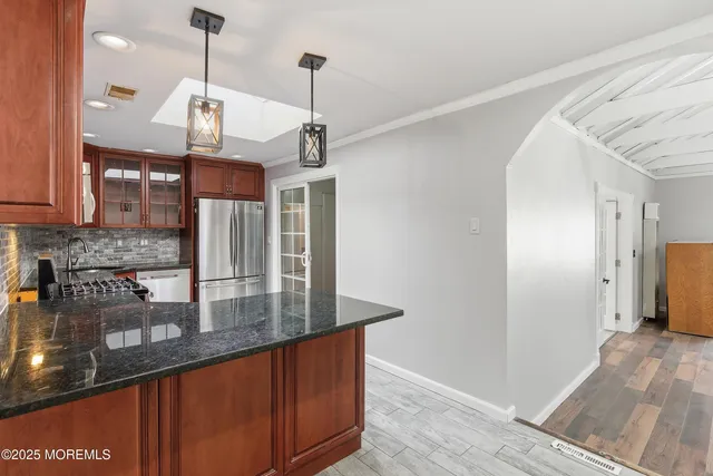 a kitchen with stainless steel appliances granite countertop a sink a refrigerator and a wooden floor