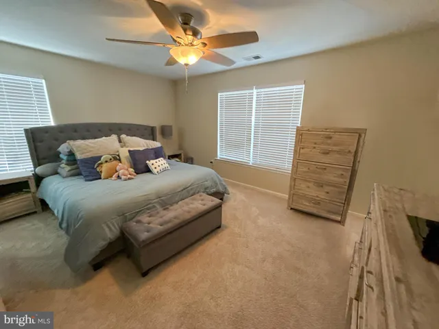 a spacious bedroom with a bed a dresser and a window