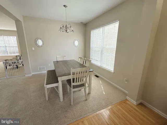 a dining room with wooden floor and a chandelier