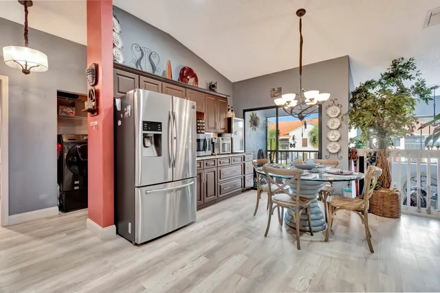 a open kitchen with stainless steel appliances granite countertop a dining table chairs and a chandelier