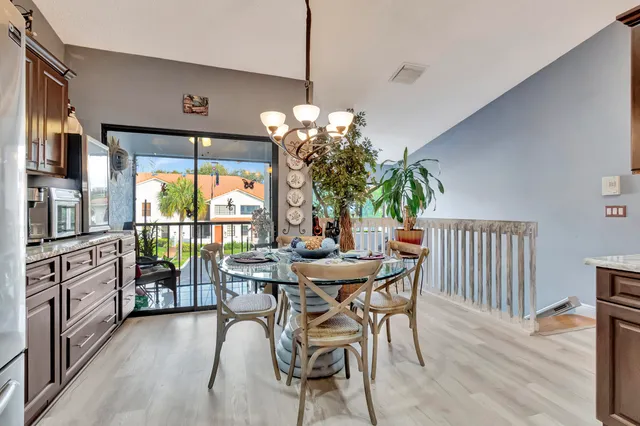a dining room with furniture wooden floor a potted plant and a chandelier