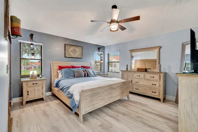 a spacious bedroom with a bed and a flat tv screen on the dresser