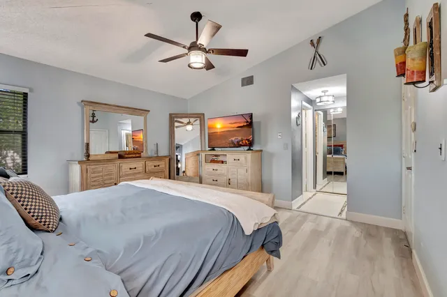 a bedroom with a large bed a flat tv screen and a dresser