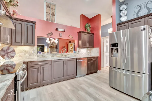 a kitchen with granite countertop stainless steel appliances a refrigerator a sink and cabinets