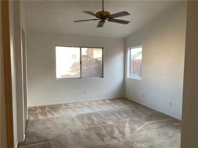 an empty room with windows and fan