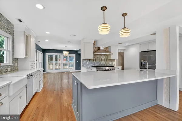 a large kitchen with stainless steel appliances a large center island attached withe living room