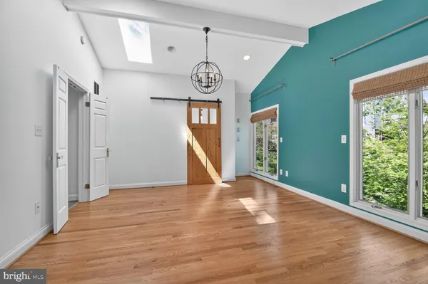 a view of an empty room with wooden floor and window
