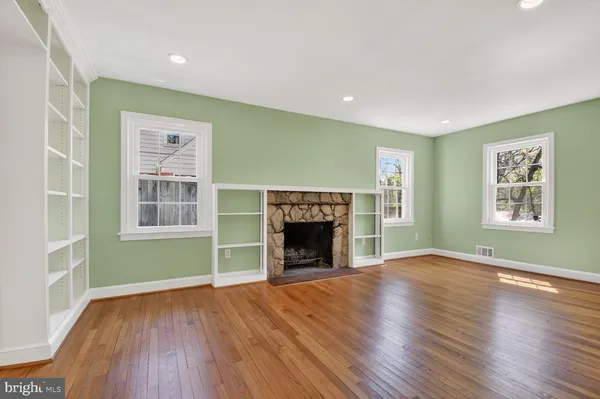 wooden floor fireplace and windows in an empty room