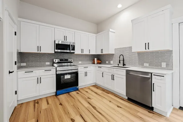 a kitchen with granite countertop a sink cabinets and stainless steel appliances