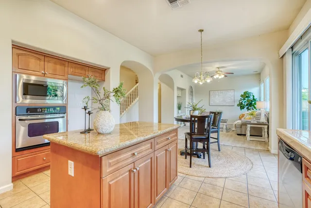 a kitchen with stainless steel appliances granite countertop a stove a sink a refrigerator and a dining table