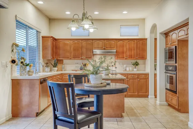 a kitchen with kitchen island granite countertop wooden cabinets and refrigerator