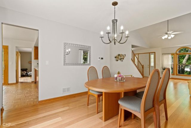 a dining room with wooden floor a chandelier a wooden table and chairs