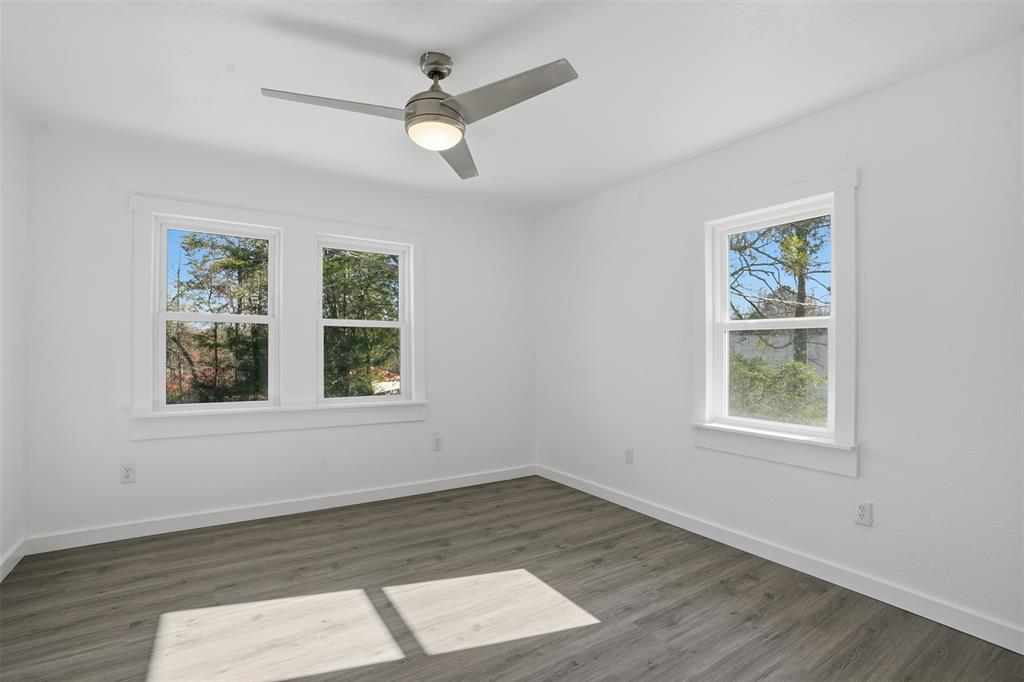 3148 Medlin Road East Mountain, TX 75645 - Photo 17 of 36 an empty room with wooden floor windows and a ceiling fan