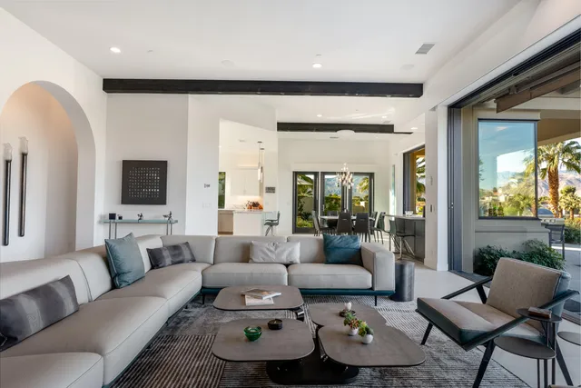 a living room with furniture a flat screen tv and floor to ceiling window