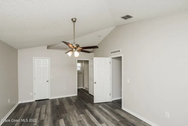 a view of an empty room with window and a ceiling fan