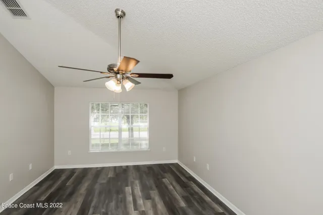 a view of a room with window ceiling fan and wooden floor