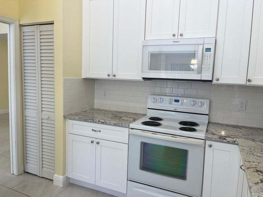7722 Solimar Circle Boca Raton, FL 33433 - Photo 8 of 36 a kitchen with white cabinets and white appliances