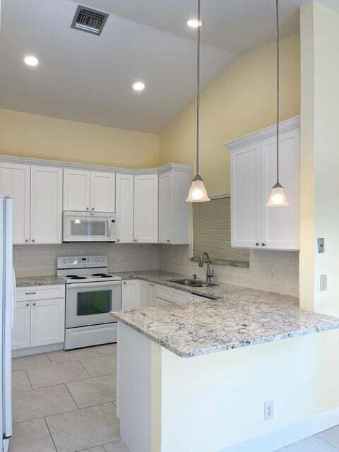 7722 Solimar Circle Boca Raton, FL 33433 - Photo 9 of 36 a kitchen with kitchen island granite countertop a stove a sink and a refrigerator