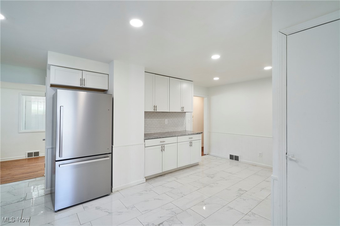 4037 Suffolk Road Cleveland, OH 44121 - Photo 13 of 26 Kitchen with backsplash, light hardwood / wood-style flooring, stainless steel refrigerator, white cabinets, and dark stone countertops