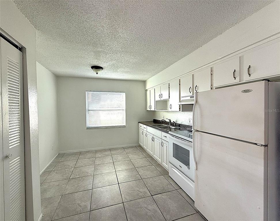 698 Michigan Court, Unit 4 St. Cloud, FL 34769 - Photo 5 of 17 a kitchen with a refrigerator a stove top oven and cabinets