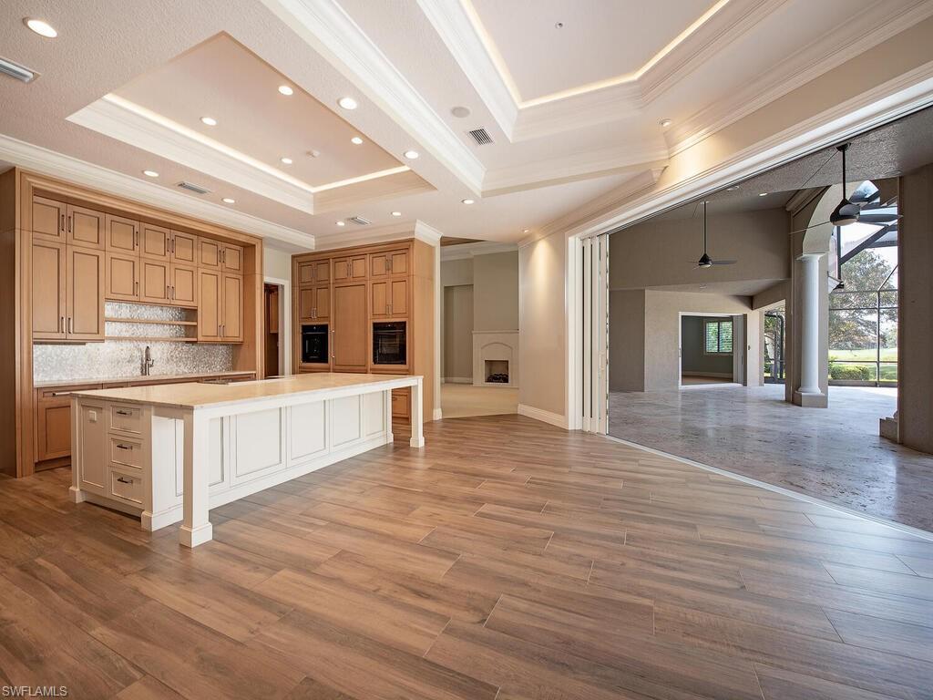 2835 Silverleaf Lane Naples, FL 34105 - Photo 16 of 50 a large white kitchen with kitchen island a stove a sink dishwasher and white cabinets with wooden floor