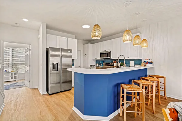 a kitchen with stainless steel appliances kitchen island granite countertop a refrigerator a stove top oven and a sink with wooden floor