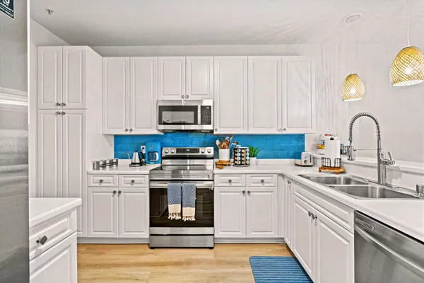 a kitchen with white cabinets appliances and a sink