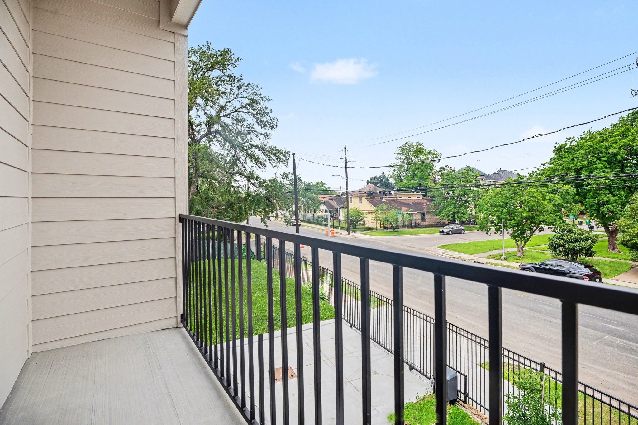 115 Milby Street Houston, TX 77003 - Photo 27 of 28 This photo shows a cozy balcony with a metal railing, overlooking a quiet neighborhood street lined with trees. The area is peaceful, offering a pleasant view of the surroundings and a great view of downtown Houston!
