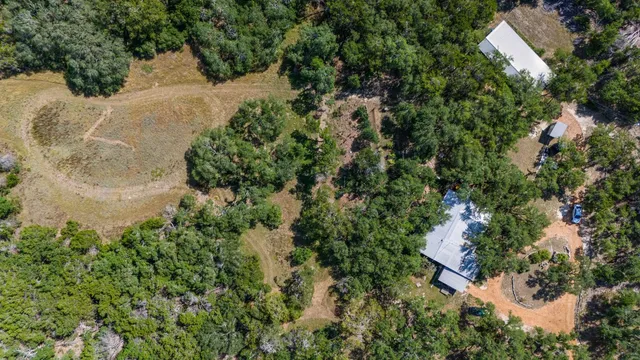 an aerial view of residential house with outdoor space and trees all around