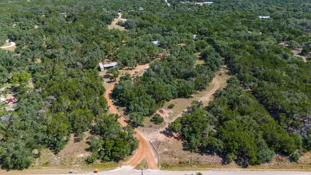 an aerial view of residential house with outdoor space and trees all around