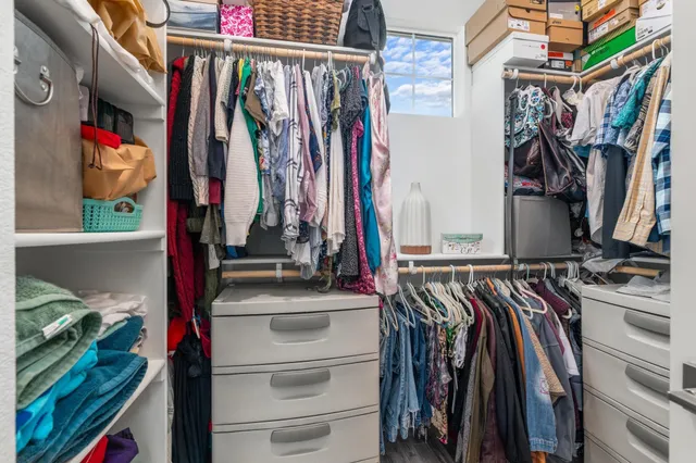 a view of walk in closet with clothes and shoes