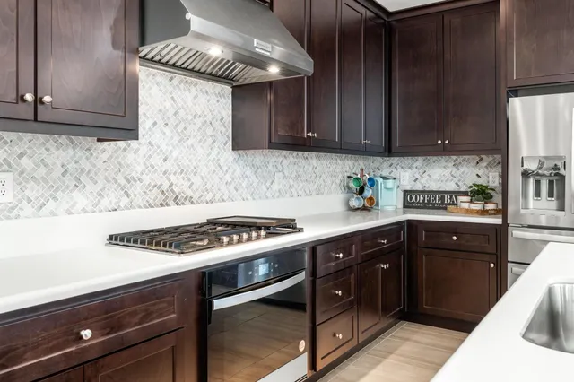 a kitchen with stainless steel appliances granite countertop a stove a sink dishwasher and cabinets with wooden floor