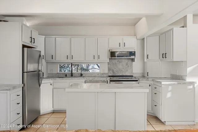 a kitchen with stainless steel appliances granite countertop white cabinets stove a refrigerator and a granite counter tops