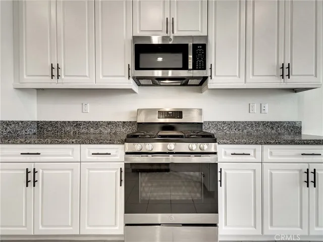 a kitchen with granite countertop white cabinets and stainless steel appliances