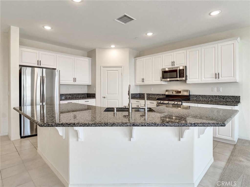 43885 Arancia Way Indio, CA 92203 - Photo 6 of 26 a kitchen with kitchen island granite countertop a stove sink and microwave