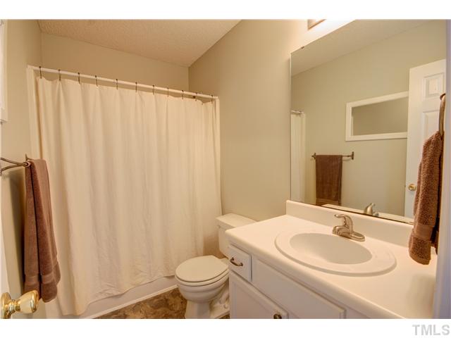 9509 Dawnshire Road Raleigh, NC 27615 - Photo 17 of 24 a bathroom with a sink a toilet a mirror and shower curtain