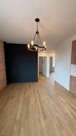 a view of a room with a hanging light and hardwood